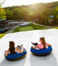 Two riders tubing downhill on an outdoor slide overlooking scenic hills as part of a Branson MO Vacation Planner experience.