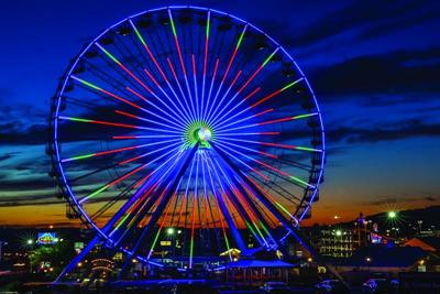 Illuminated Ferris wheel glowing against the Branson skyline at dusk, showcasing a signature nighttime attraction commonly included in itineraries.