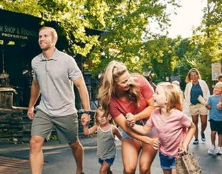 Family walking together through a lively outdoor attraction, smiling and engaging with the surroundings, highlighting flexible travel planning and guest-friendly options covered under the Cancellation policy for Branson vacation package.