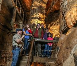 Guide and family exploring a large cave interior with towering rock formations