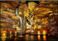 Underground cave with illuminated rock formations and calm water