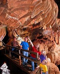 Family exploring a Branson cave attraction, Talking Rocks Cavern, walking along a guided path beneath dramatic rock formations�an educational and adventurous highlight for a Family vacation Branson MO, popular in Branson spring vacation packages and Branson summer vacation packages.