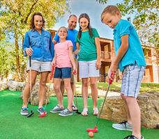 Family playing miniature golf together at a Branson attraction, smiling and enjoying an outdoor activity perfect for a Family vacation Branson MO, especially popular within Branson spring vacation packages and Branson summer vacation packages.