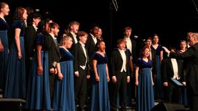 Student choir performing on stage in coordinated formal attire under professional lighting, delivering a polished choral presentation�an ideal showcase opportunity for Branson Student Performing groups during organized student travel.