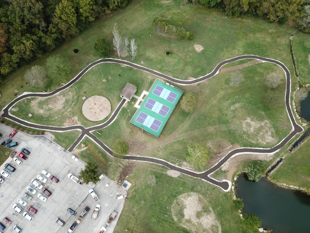 Aerial view of a walking path, pickleball and basketball courts, green space, and nearby parking, highlighting budget friendly Branson MO recreation and outdoor fun.