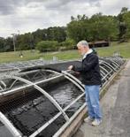 Visitor feeding trout as an outdoor hands-on educational exhibit.